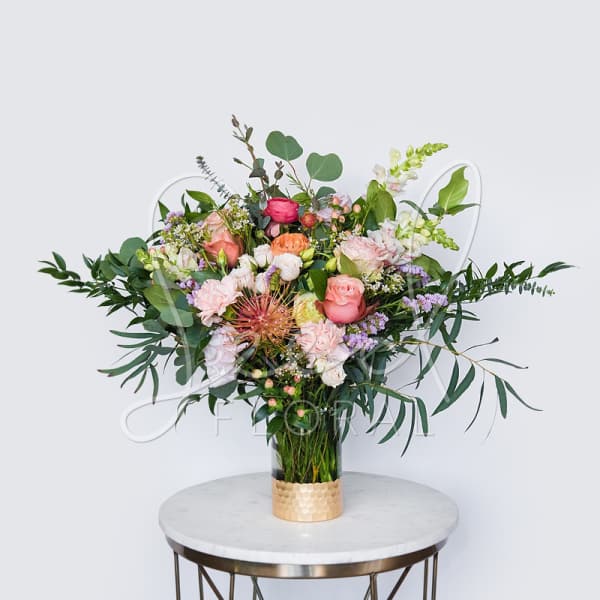 Mixed bouquet of pink, peach, and white flowers in a glass vase