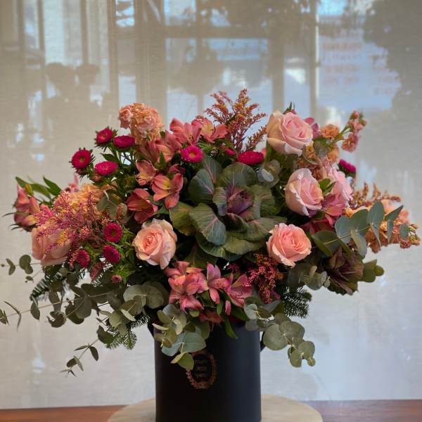 Pink and peach floral arrangement in a black vase