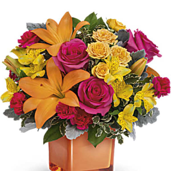 Bright bouquet of orange lilies, pink roses, and yellow flowers in an orange vase
