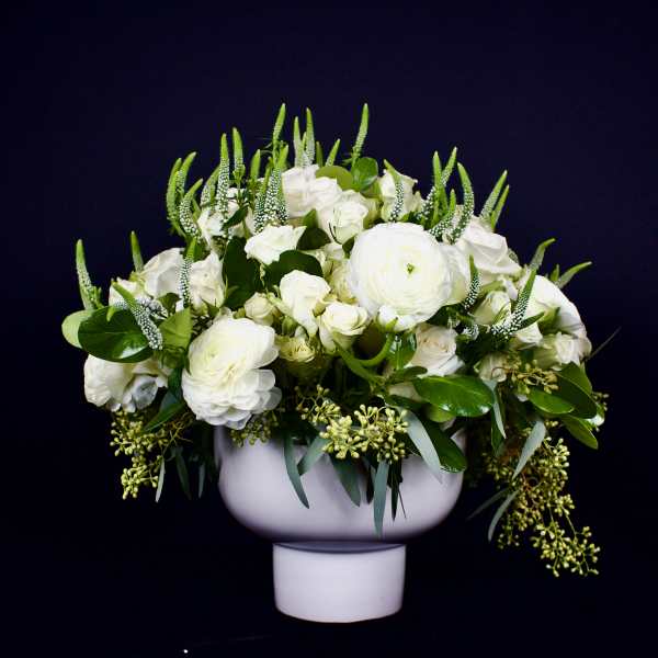 White floral arrangement in a white pedestal vase