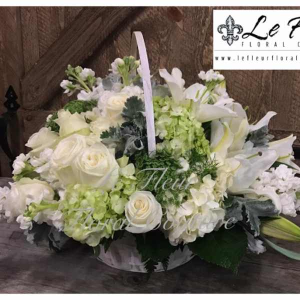 White floral arrangement in a low basket with lilies and roses