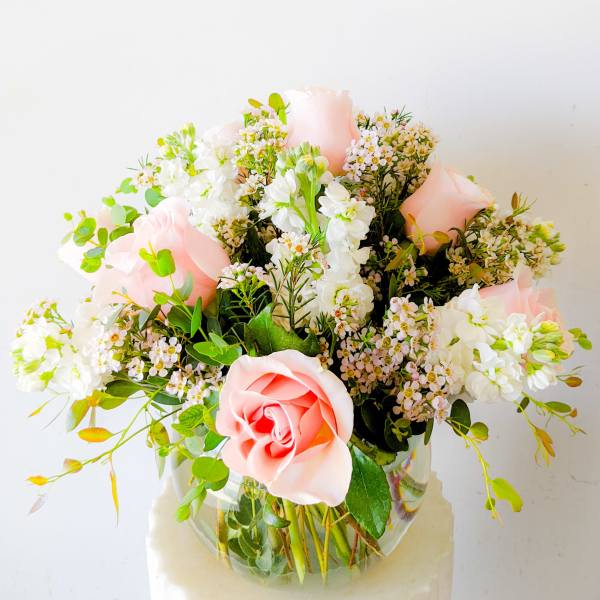 Pink roses and white flowers arranged in a clear glass vase
