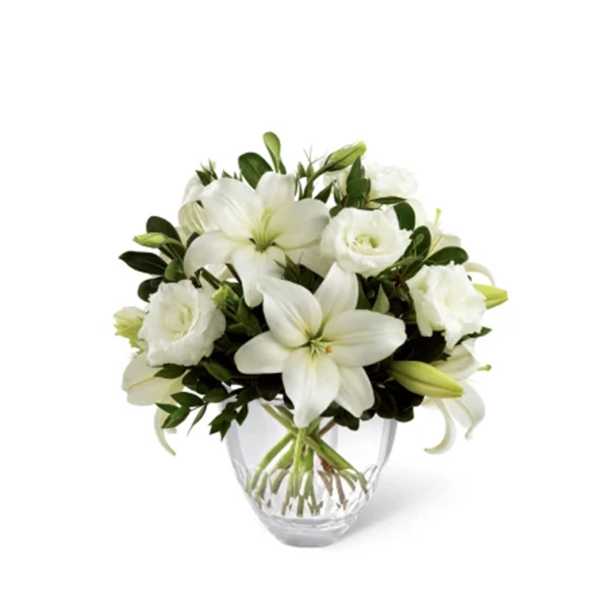 White lilies and roses arranged in a clear glass vase