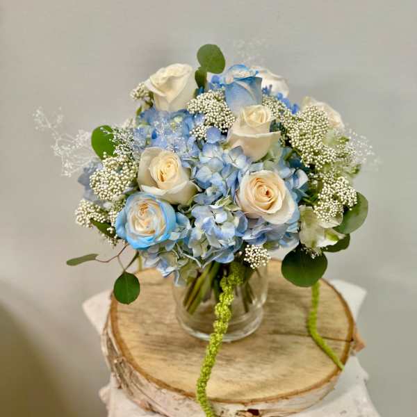 Blue hydrangea and cream roses in a clear glass vase