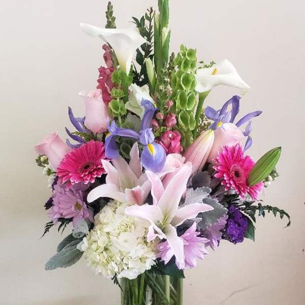 Mixed bouquet with lilies, calla lilies, gerbera daisies, and hydrangea in a glass vase