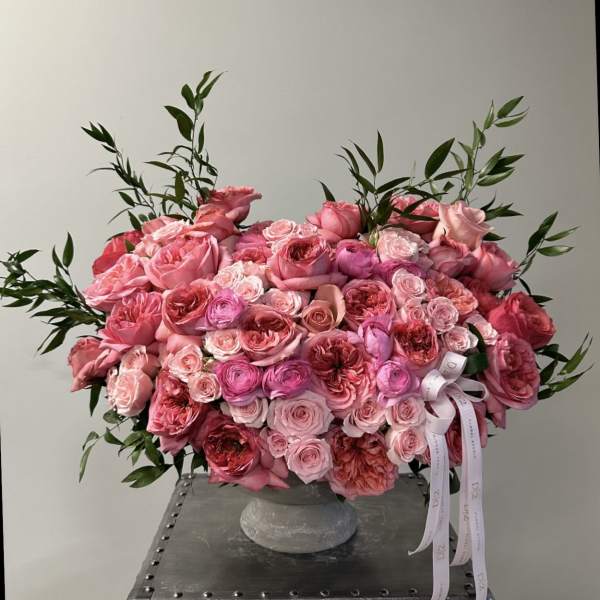 Large pink rose arrangement in a gray vase with ribbon tails