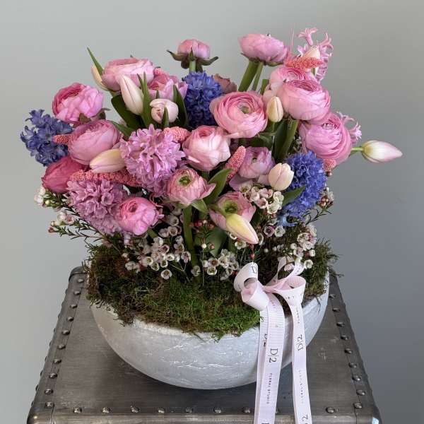 Pink and blue mixed flower arrangement in a round silver bowl