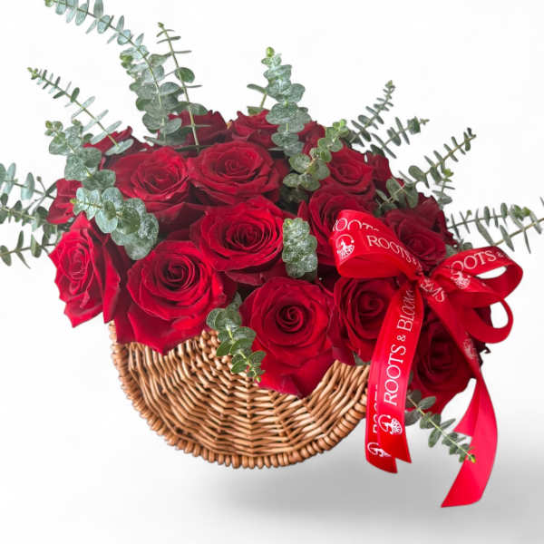 Red roses in a wicker basket with eucalyptus and a red ribbon