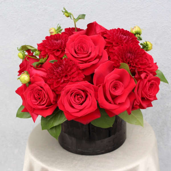 Red roses and red mums arranged in a black round box