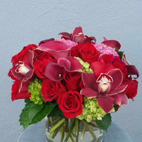 Red roses and burgundy calla lilies in a clear glass vase