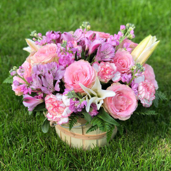 Pink and lavender flower arrangement in a wooden basket