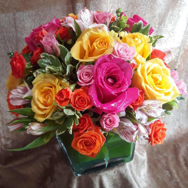 Mixed bouquet of roses and alstroemeria in a square glass vase