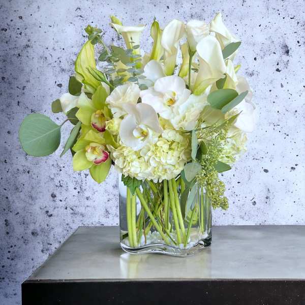 White and pale green floral arrangement in a clear glass vase