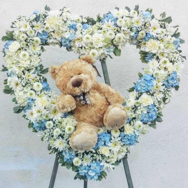 Heart-shaped floral wreath with a teddy bear in the center