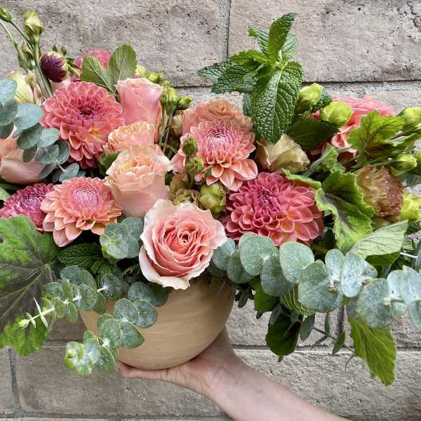 Pink roses and dahlias in a round vase with eucalyptus