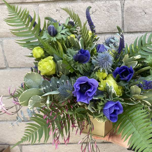 Blue and yellow floral arrangement in a gold box