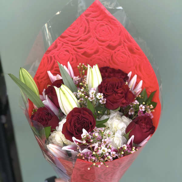 Bouquet of deep red roses and white lilies wrapped in red paper