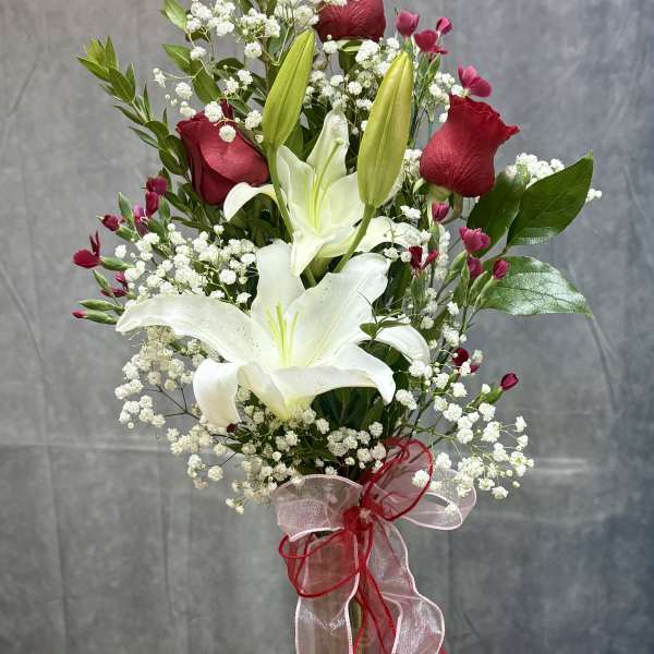 Tall bouquet of white lilies and red roses in a glass vase
