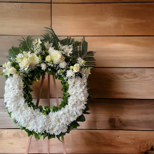 White floral funeral wreath on a wooden easel