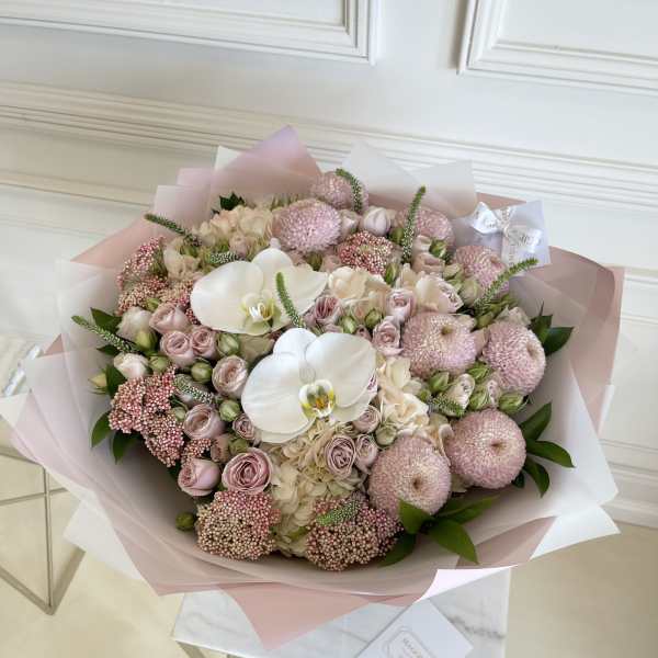 Large pastel bouquet with white orchids and pink roses wrapped in pink paper