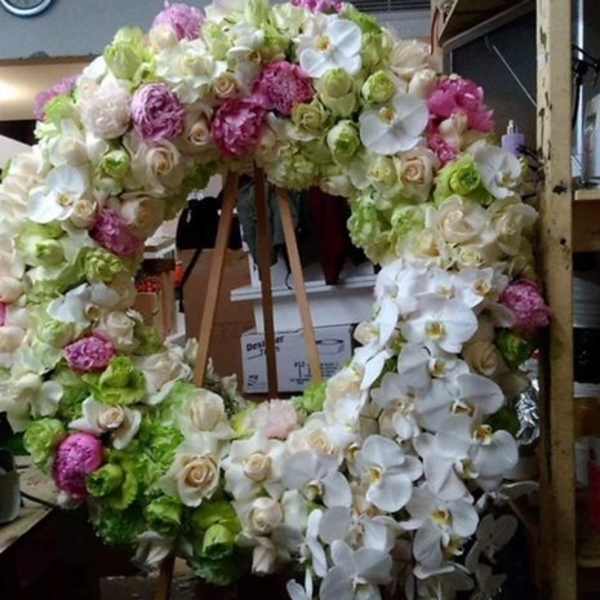 Large floral wreath on a wooden stand with white, pink, and green blooms