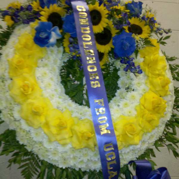 Large floral wreath with yellow roses, white flowers, and blue blooms