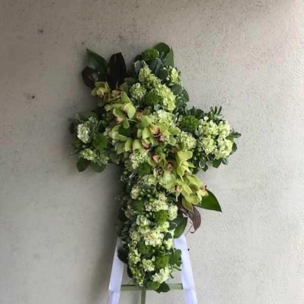 Cross-shaped floral spray with green flowers on a stand