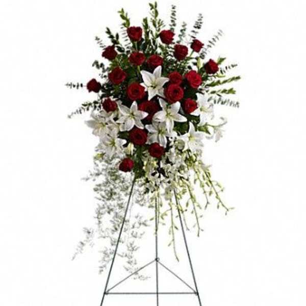 Standing floral spray with red roses and white lilies on an easel