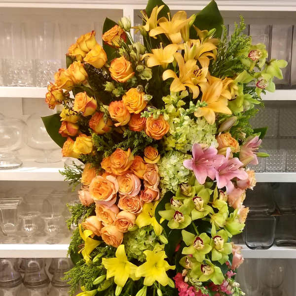 Large standing spray of yellow, orange, pink, and green flowers