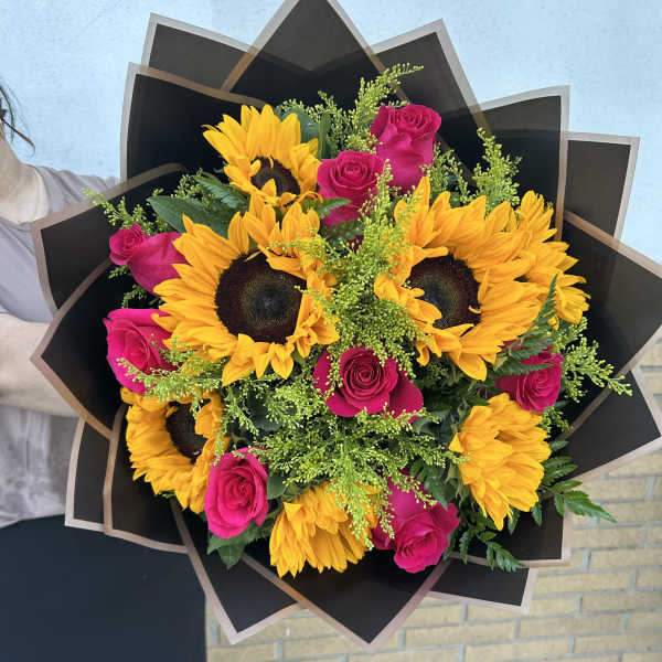 Bouquet of yellow sunflowers and hot pink roses wrapped in black paper