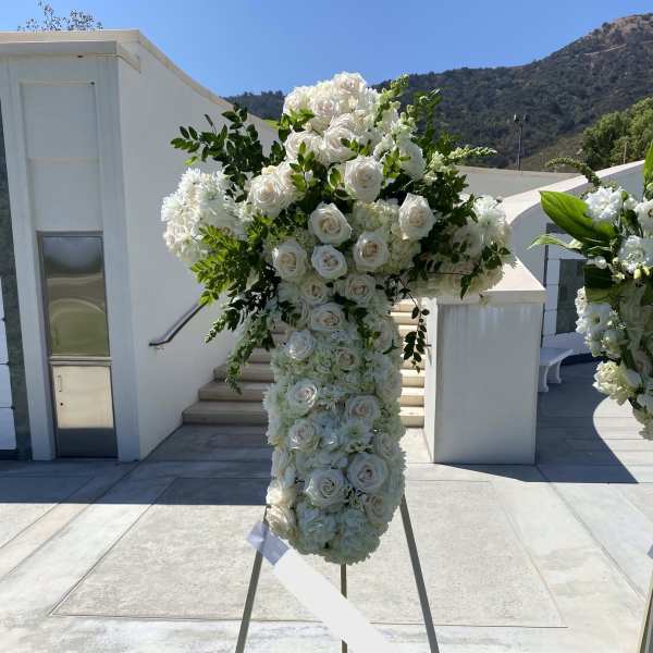 Tall standing white rose and hydrangea sympathy spray on an easel outdoors
