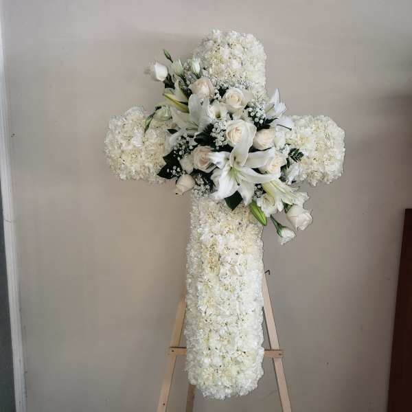 White floral cross arrangement on a wooden easel