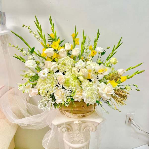 Large white and yellow floral arrangement in a wooden container