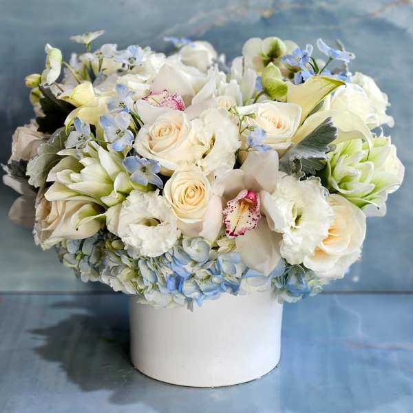 White and pale blue floral arrangement in a white vase
