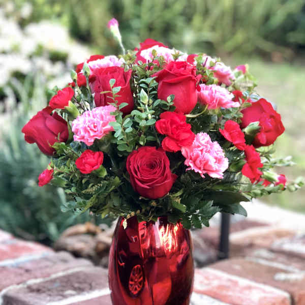 Red roses and pink carnations in a red glass vase