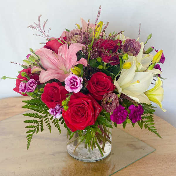 Mixed bouquet of roses, lilies, and carnations in a glass vase