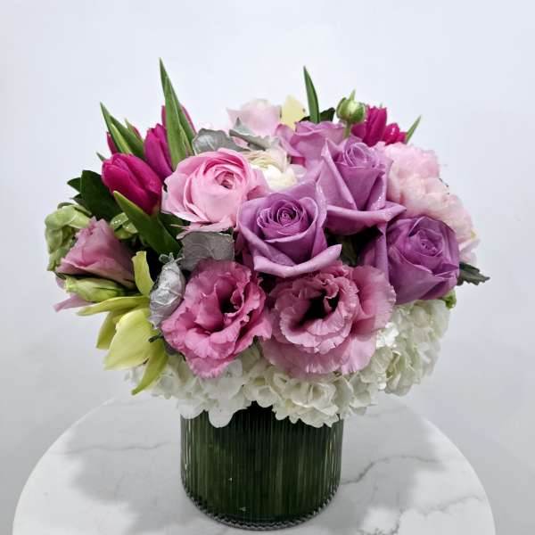 Pink and purple bouquet in a ribbed glass vase