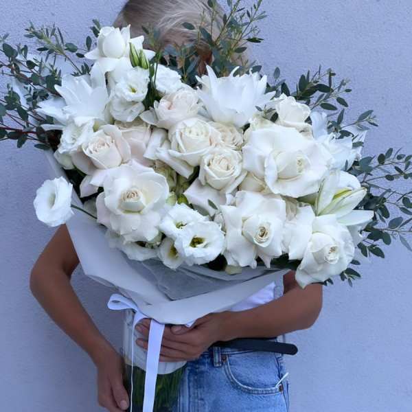 Large white bouquet of roses and lilies wrapped in paper