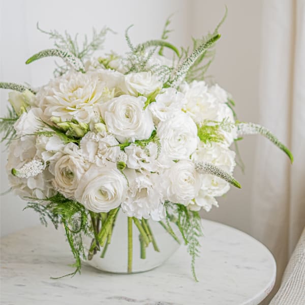 White floral bouquet in a clear glass vase on a round table