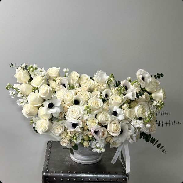 Cream rose arrangement with white anemones in a silver vase