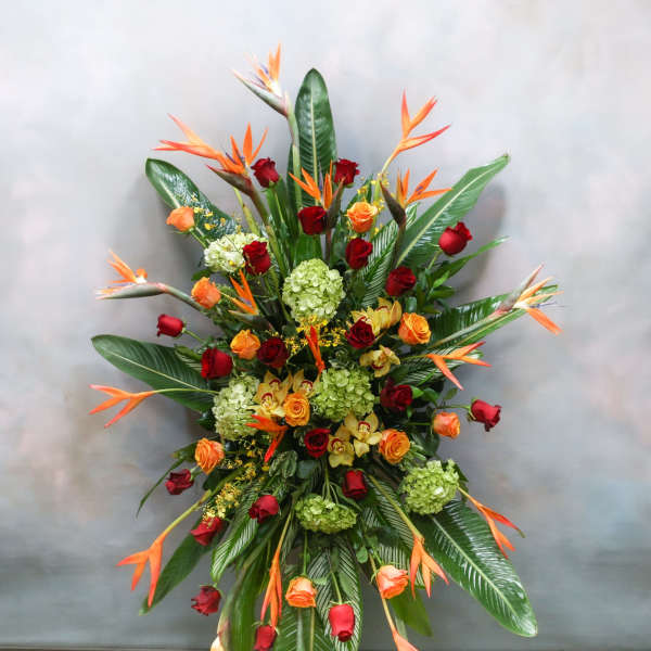 Tall tropical arrangement with roses, hydrangeas, and orange bird-of-paradise flowers