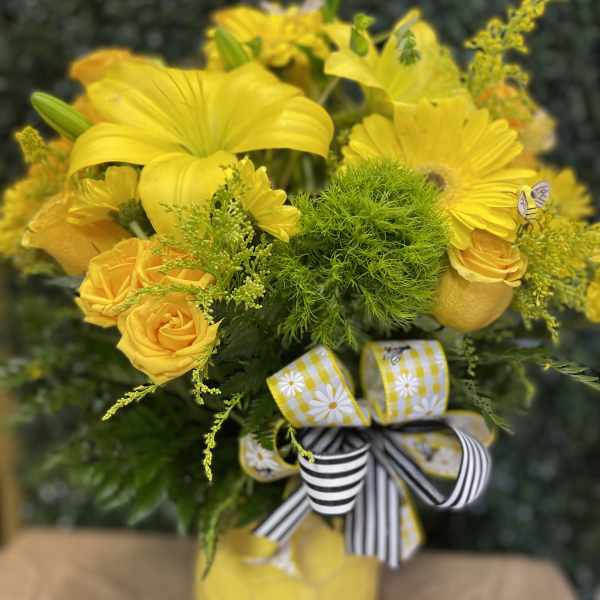 Yellow floral bouquet in a vase with striped ribbon