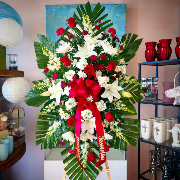 Large standing floral spray with red and white flowers and a red ribbon