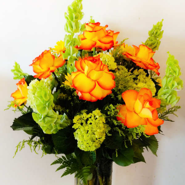 Orange roses with green snapdragons in a glass vase