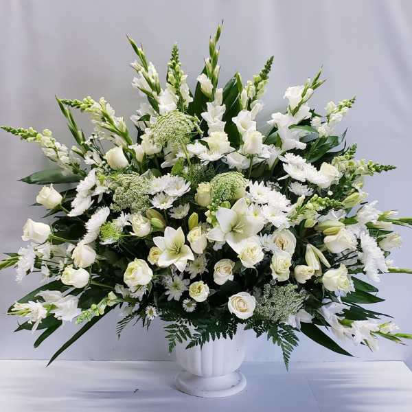 Large white floral arrangement in a white pedestal vase
