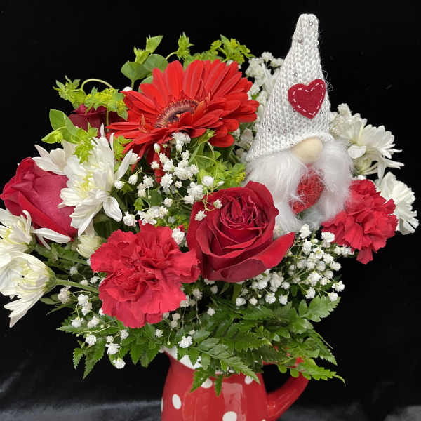 Red and white flower arrangement in a polka-dot mug with a gnome decoration