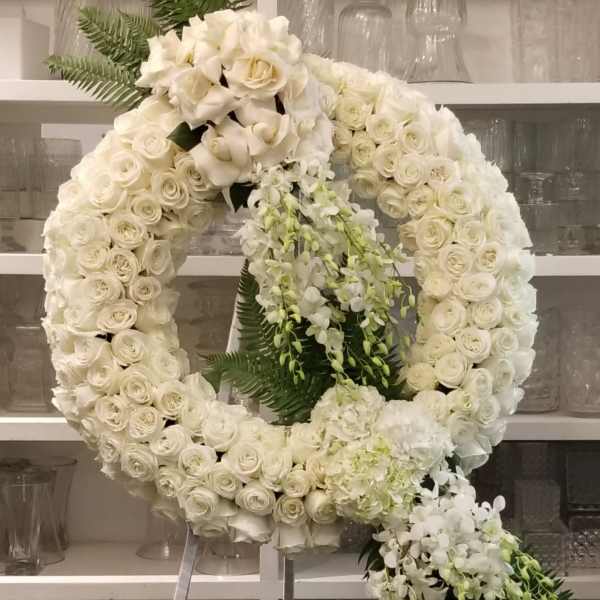 Large white floral wreath on a stand with cascading orchids