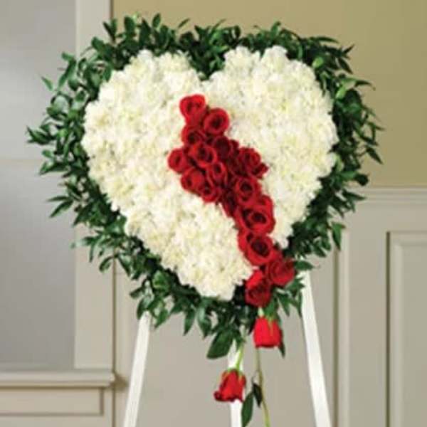 Heart-shaped white floral spray with red roses on a standing easel