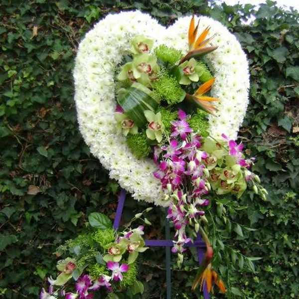 Heart-shaped floral wreath with orchids and bird-of-paradise on a stand