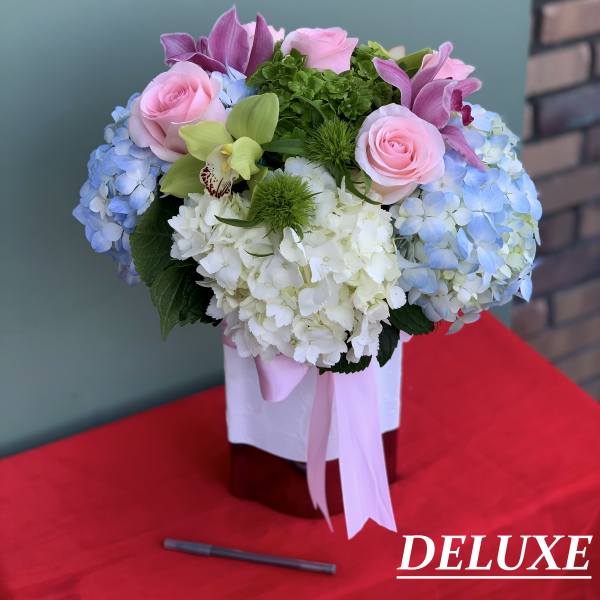 Pink roses and blue hydrangeas in a ribbon-tied box arrangement
